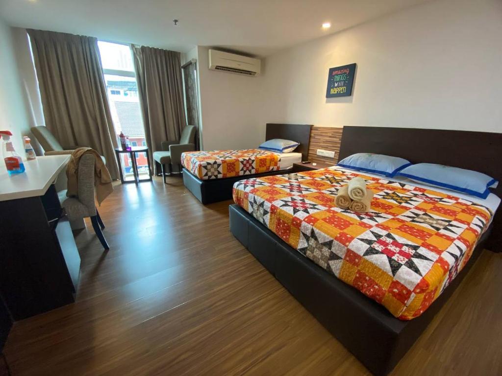 a hotel room with two beds and a table at Cyber Studio Apartment in Kota Bharu