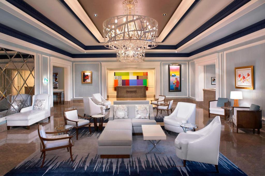 a living room with white furniture and a chandelier at The Henry, Autograph Collection in Dearborn