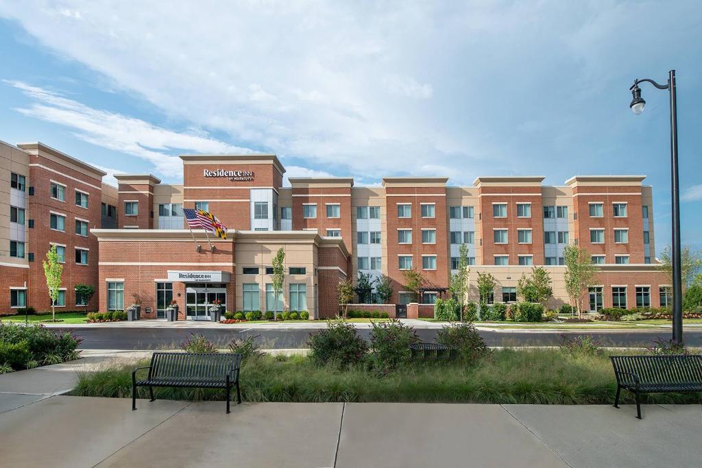 zwei Bänke vor einem großen Gebäude in der Unterkunft Residence Inn Fulton at Maple Lawn in Fulton