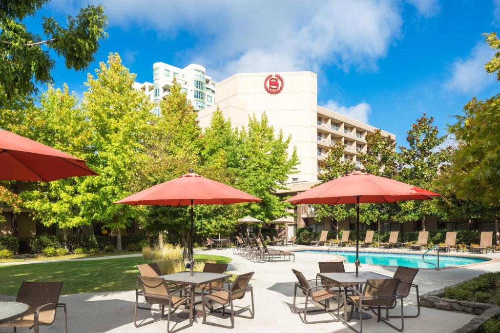 un patio con tavoli e ombrelloni accanto alla piscina di Sheraton Vancouver Airport Hotel a Richmond