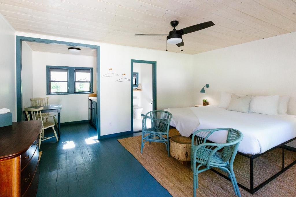 a bedroom with a bed and chairs and a kitchen at Piety Hill Cottages in Nevada City