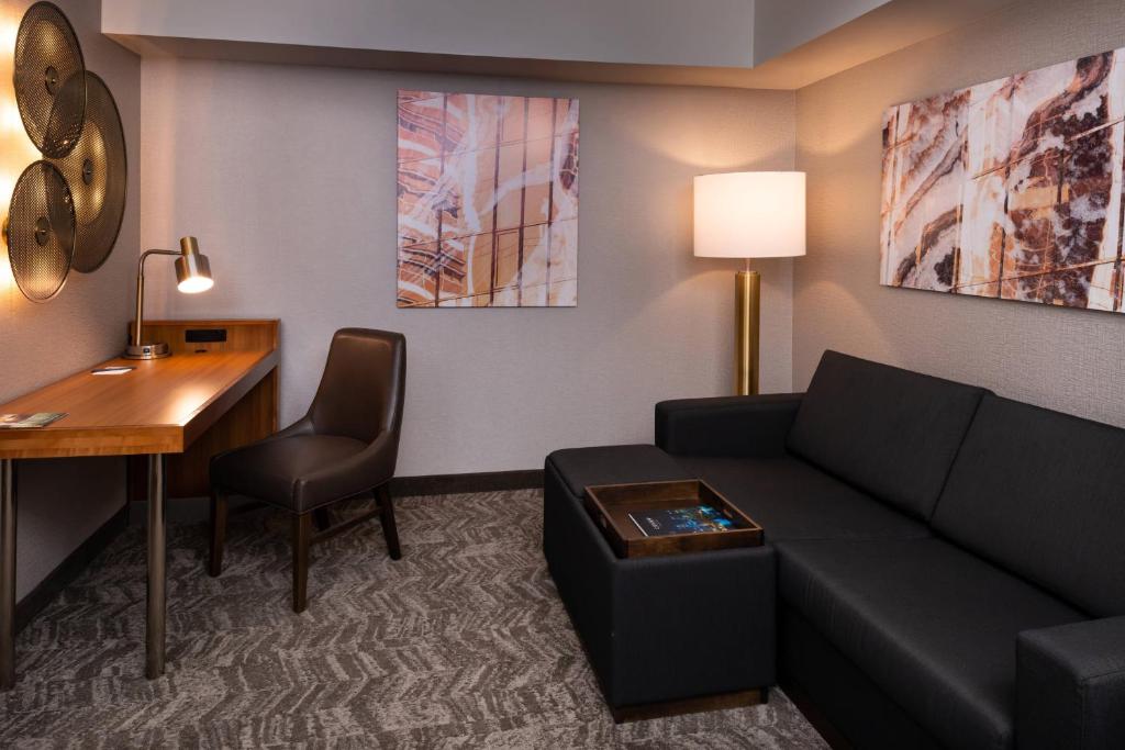 una sala de estar con sofá y escritorio en una habitación de hotel en SpringHill Suites by Marriott Pittsburgh North Shore, en Pittsburgh