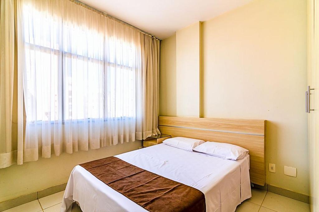 um quarto com uma cama e uma grande janela em Villa Neves Residence em Belo Horizonte