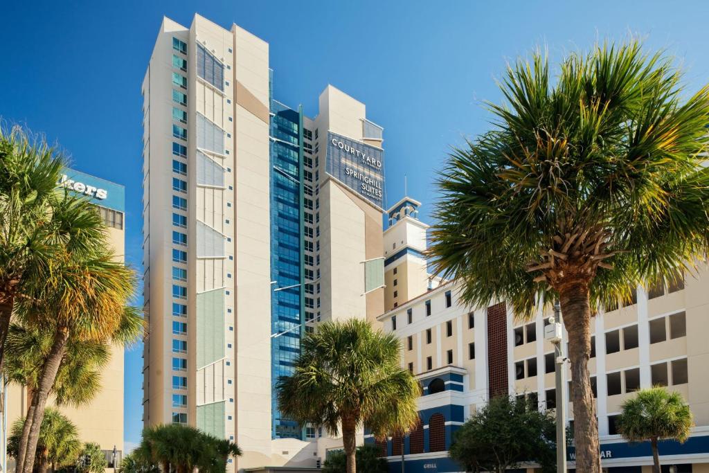 ein hohes Gebäude mit Palmen davor in der Unterkunft SpringHill Suites by Marriott Myrtle Beach Oceanfront in Myrtle Beach