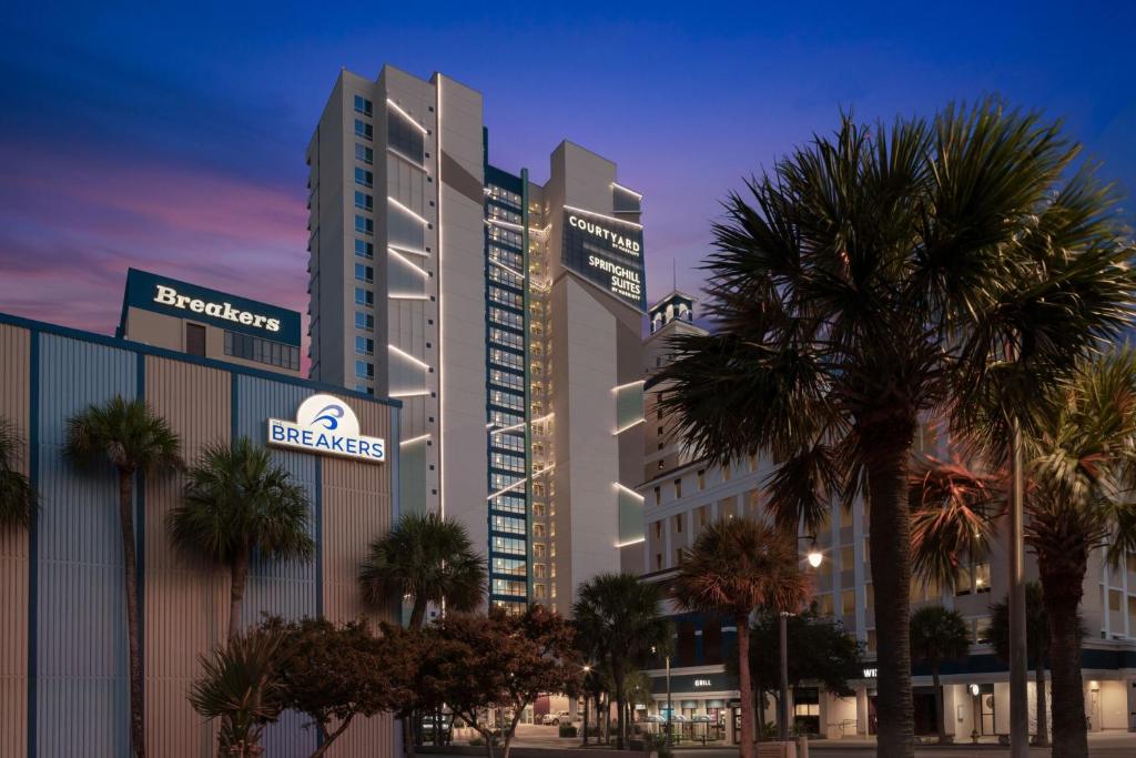 ein großes Gebäude mit Palmen davor in der Unterkunft SpringHill Suites by Marriott Myrtle Beach Oceanfront in Myrtle Beach