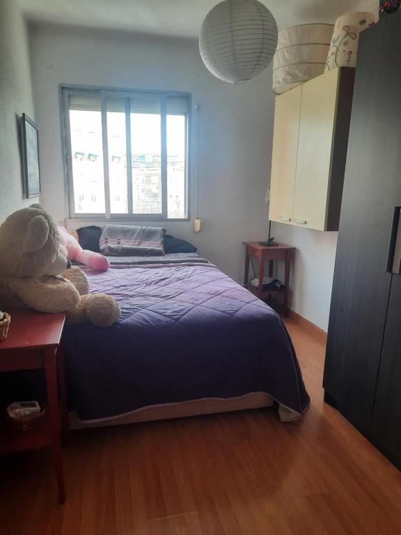 Un dormitorio con una cama con un osito de peluche. en Una Habitación Individual en casa familiar dentro de Ciudad Patrimonio de la Humanidad, en Alcalá de Henares
