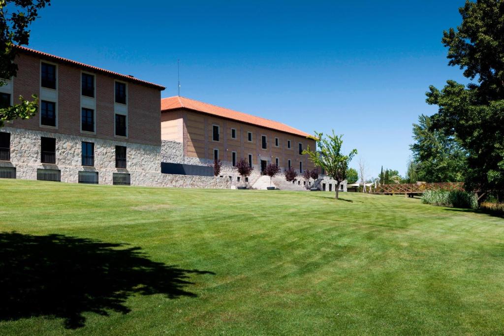 a building with a large lawn in front of it at AC Hotel Palacio de Santa Ana by Marriott in Valladolid