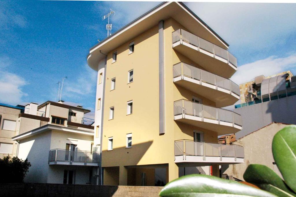 ein gelbes Gebäude mit Balkon an der Seite in der Unterkunft Apartments in Lignano 21702 in Lignano Sabbiadoro