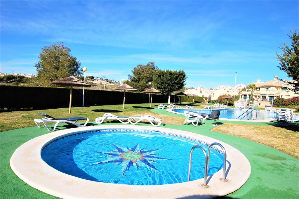 a swimming pool in a yard with chairs at Beautiful house in Campoamor Golf in Villacosta