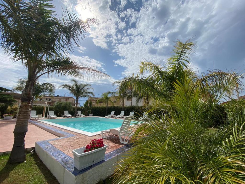 una piscina con sedie e una palma di Verter Home Resort a Ovile la Marina