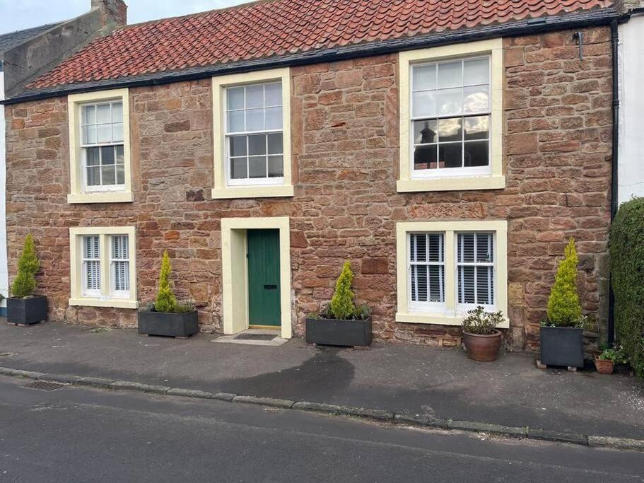 a brick house with a green door and potted plants at Seahorses Crail in Crail