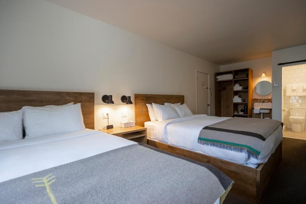 a hotel room with two beds and a bathroom at Hotel Mont-Tremblant in Mont-Tremblant