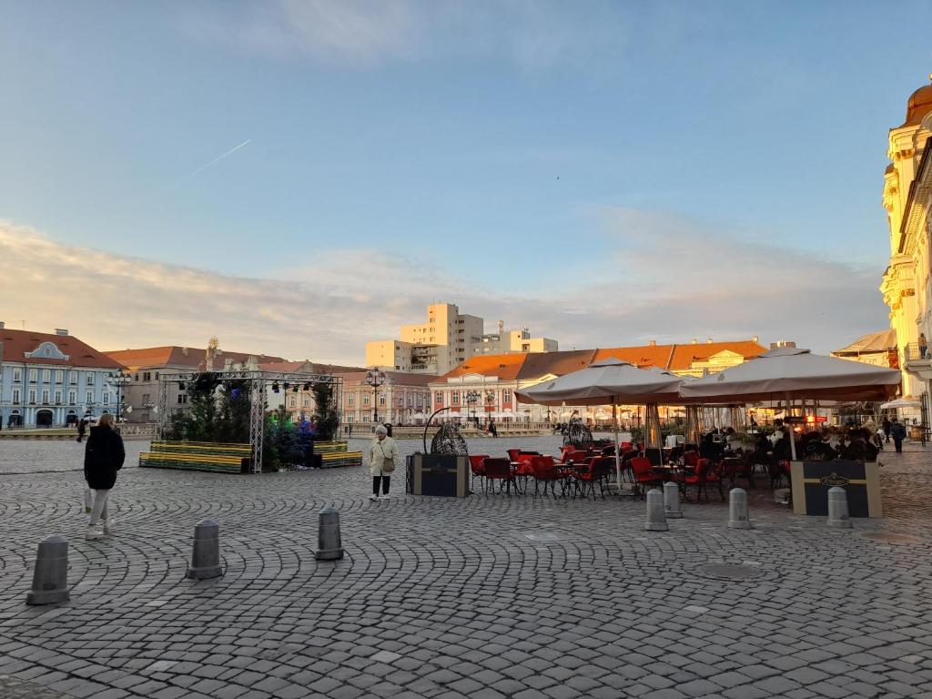 a street with tables and umbrellas in a city at Piata Unirii- 1 Room Studio Apartment in Timişoara