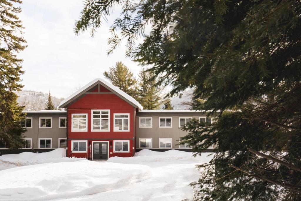 ein rotes Gebäude im Schnee vor einem Gebäude in der Unterkunft Le Couvent Val-Morin in Val-Morin