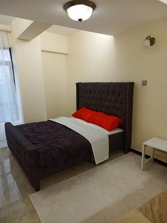 um quarto com uma cama grande e uma almofada vermelha em Lux Suites Dennis Pritt studio Apartments Kilimani em Nairobi