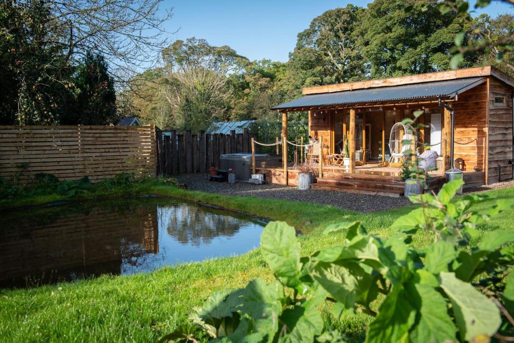 a wooden cabin with a pond in a yard at The Chard, Netherby, near Carlisle in Longtown