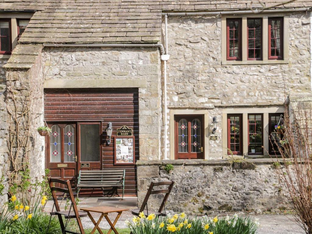 een stenen huis met een tafel en stoelen ervoor bij The Hayloft at Tennant Barn in Skipton