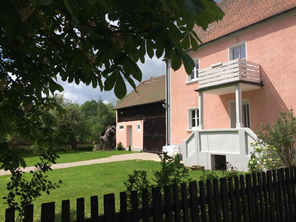 Landhaus am Schloss في Schnabelwaid: منزل وردي أمامه سياج