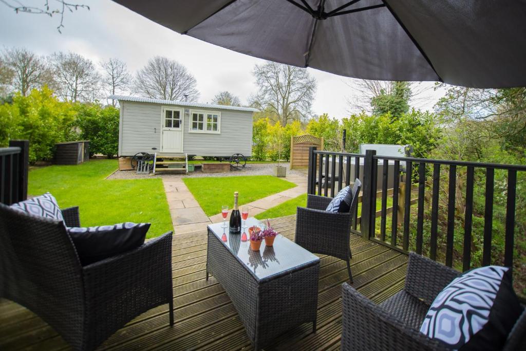 a deck with a table and chairs and an umbrella at The Snug, Netherby, near Carlisle in Longtown