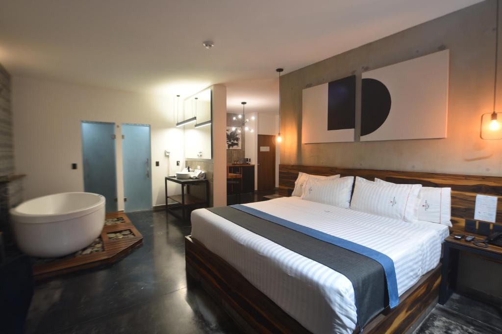 a bedroom with a large bed and a bath tub at Hangar Inn Select Aeropuerto Guadalajara in Guadalajara