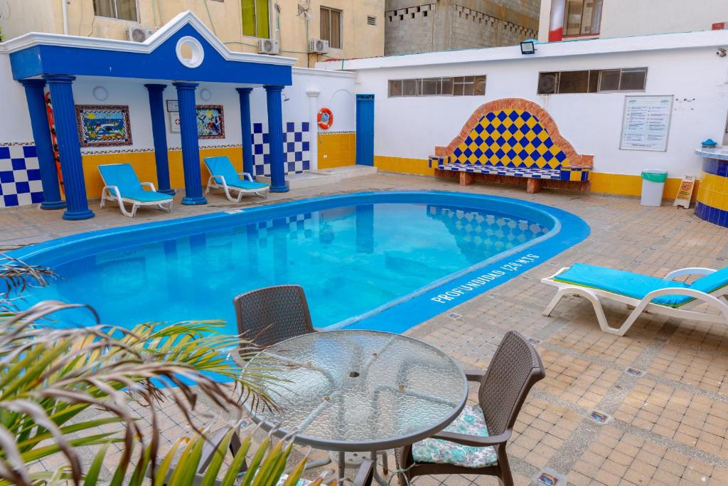 a swimming pool with a table and chairs next to it at Hotel Edmar in Santa Marta