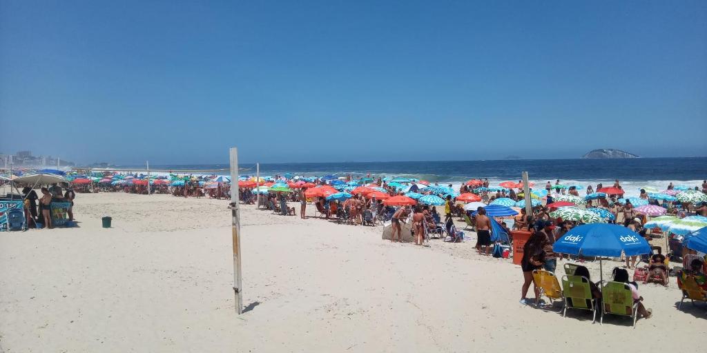 un gran grupo de personas en una playa con sombrillas en Leblon beach, en Río de Janeiro