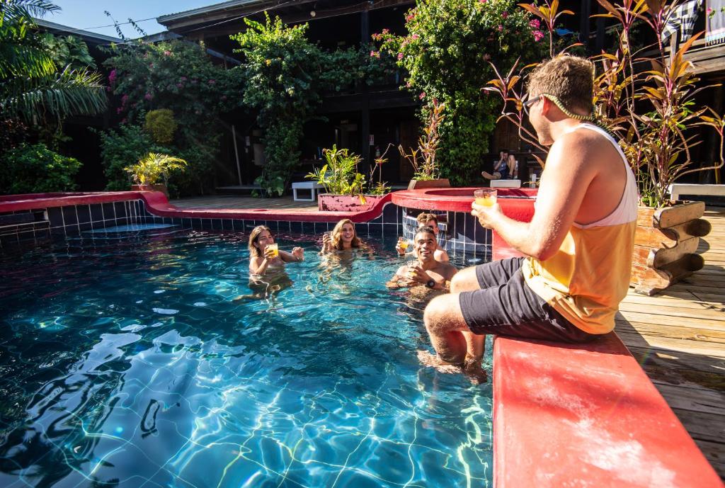 un hombre sentado en una cornisa en una piscina en Mango Inn Resort, en Utila