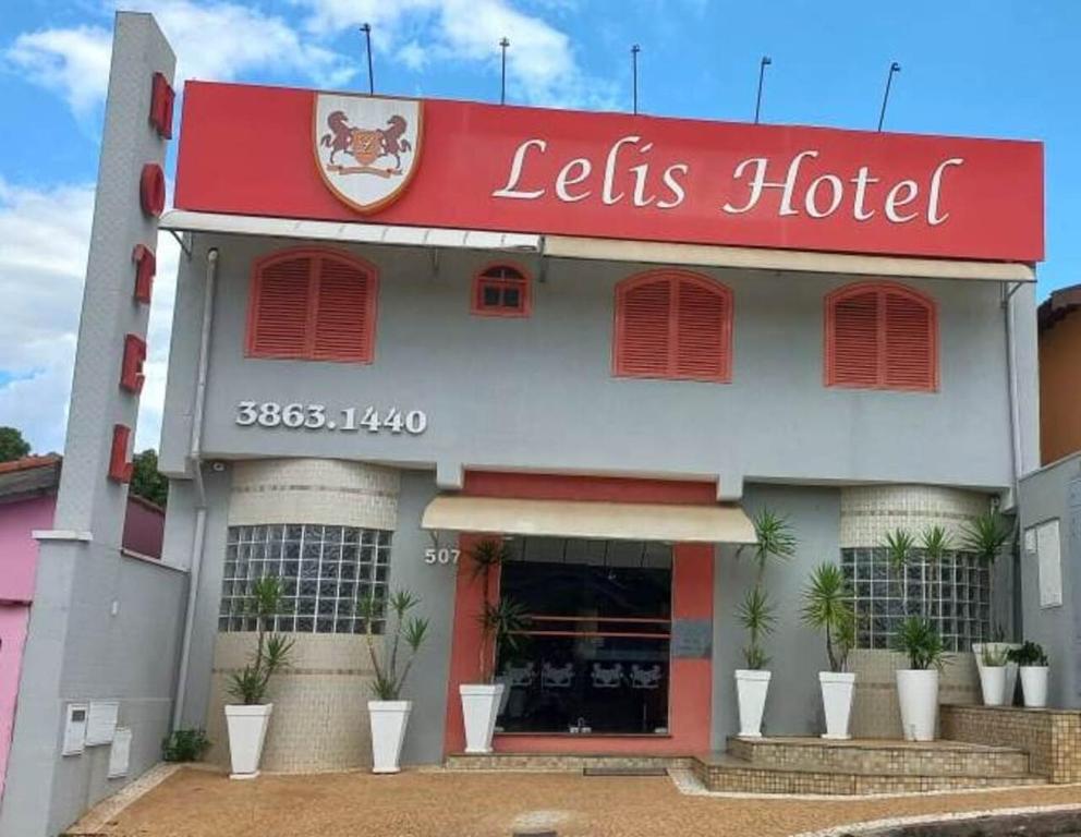 a hotel with a red sign on the front of it at Lelis Hotel in Itapira