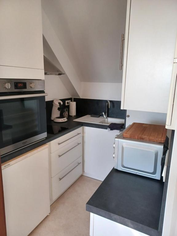 a small kitchen with white cabinets and a sink at Joli Appartement avec vue sur la Baie in Avranches