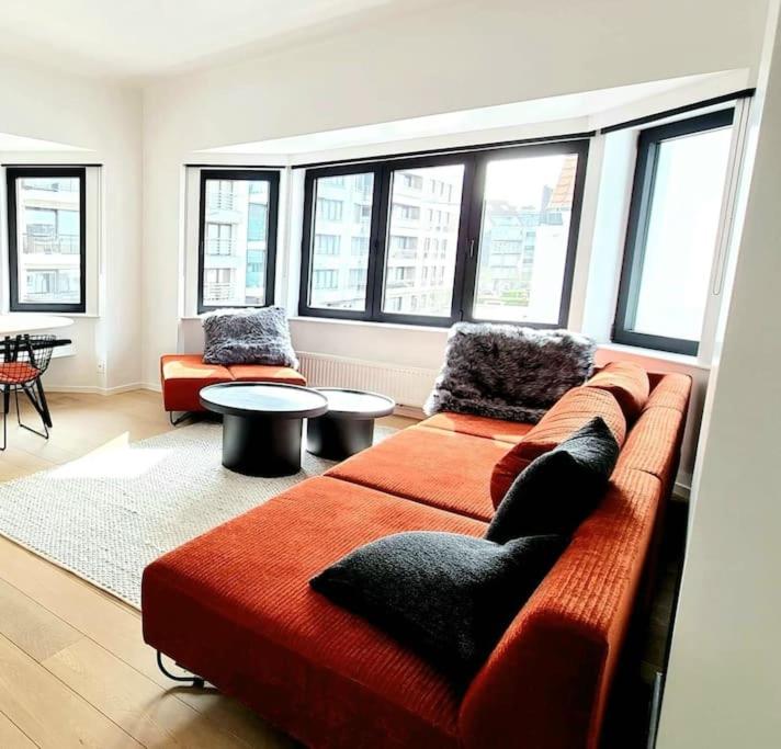 een woonkamer met een rode bank en ramen bij Cofa'sea designvol appartement in Knokke-Heist
