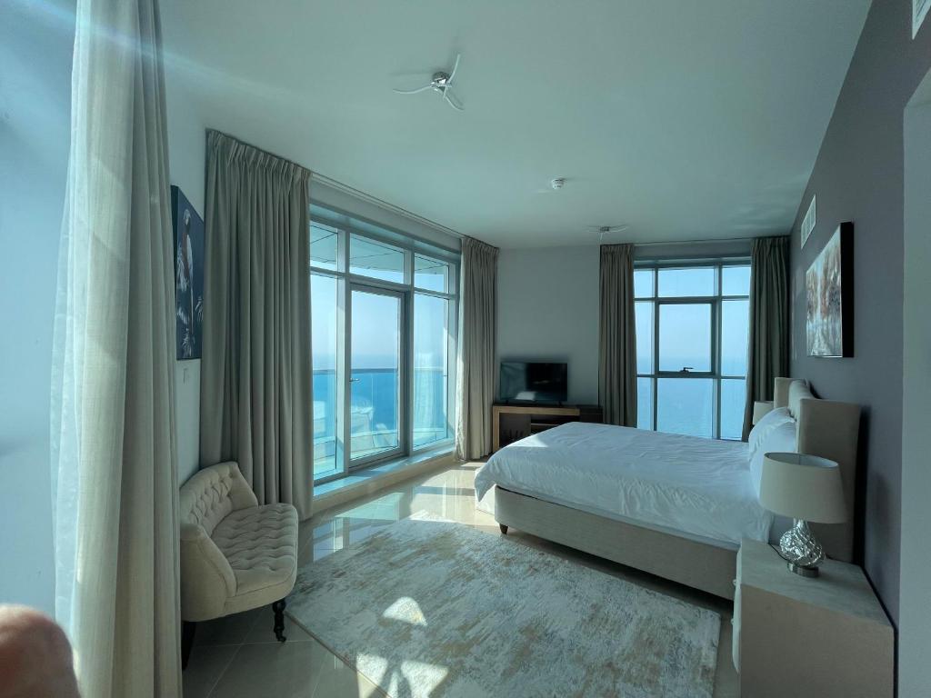 um quarto com uma cama, uma cadeira e janelas em Beachfront paradise just minutes from Dubai em Ajman