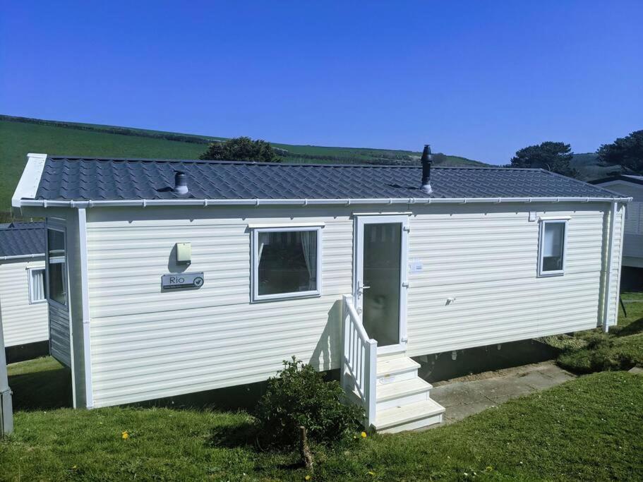 a white house with a staircase in a yard at Large 4 person Couples and Family Caravan in Newquay Bay Resort in Newquay