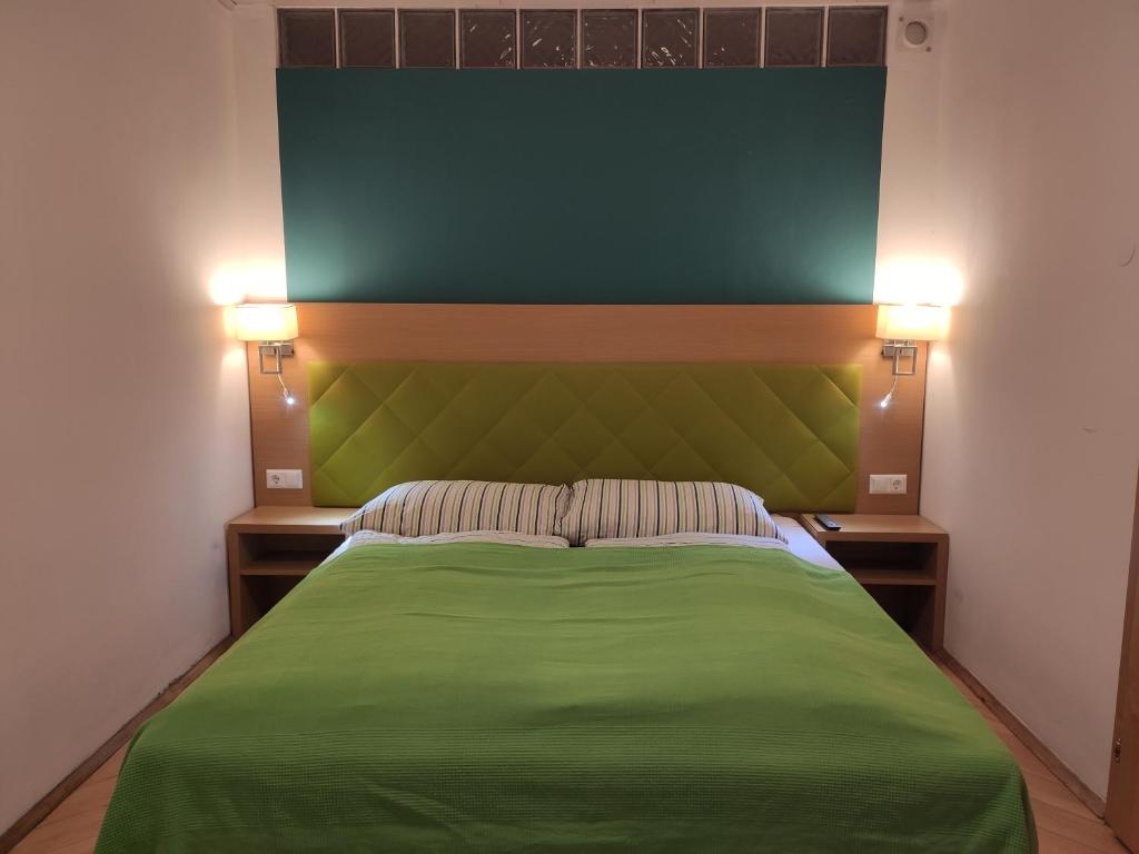 Un dormitorio con una cama verde con dos luces. en Vintage Apartment en Graz
