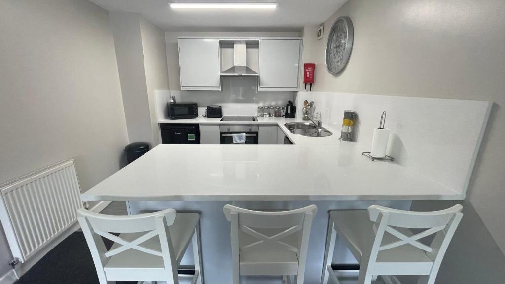 a kitchen with a white counter and two stools at Hosted By Ryan - 2 Bedroom Apartment in Liverpool