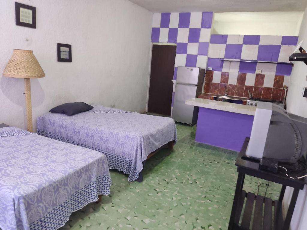 a room with two beds and a tv in it at Hostal Maruvillas in Petkanché