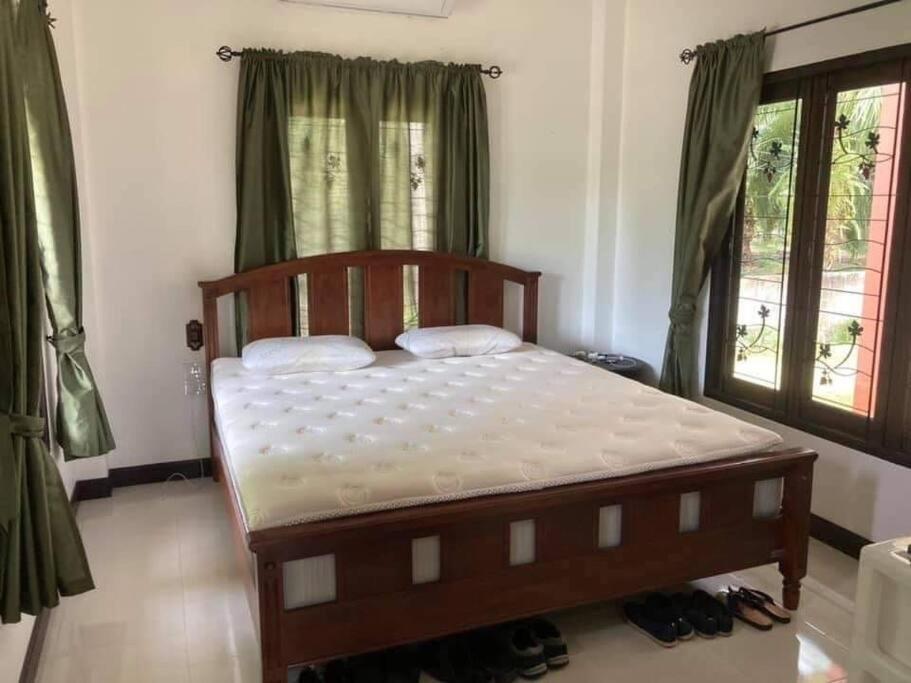 - une chambre avec un lit en bois et des rideaux verts dans l'établissement Mysigt hus i Sichon, à Sichon