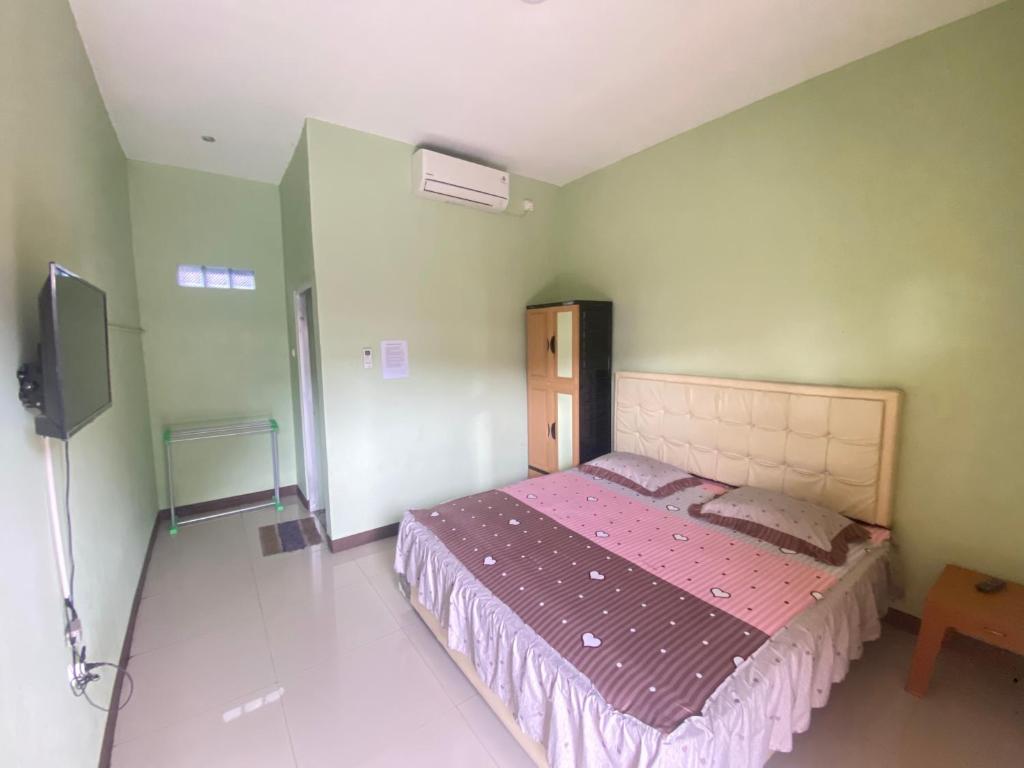 a bedroom with a bed and a tv in it at Karina Guest House Syariah in Tangkil