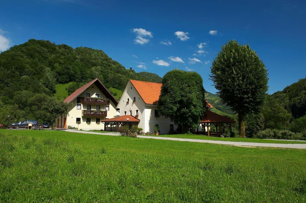 ein weißes Haus mit orangefarbenem Dach auf einem grünen Feld in der Unterkunft Tourist Farm Zelinc in Cerkno