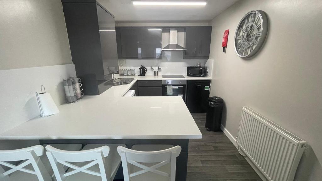a kitchen with a white counter and chairs in it at Hosted By Ryan - 2 Bedroom Apartment in Liverpool