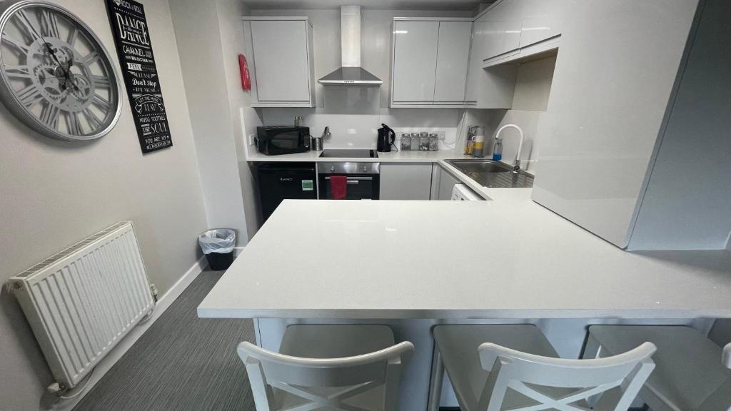 a kitchen with a white counter and chairs in it at Hosted By Ryan - 2 Bedroom Apartment in Liverpool