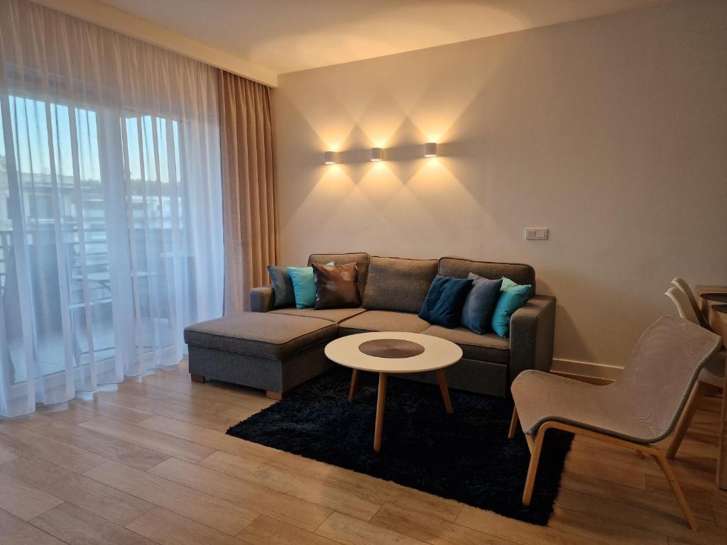 a living room with a couch and a table at Apartament Baltic Park - BEL MARE in Pogorzelica