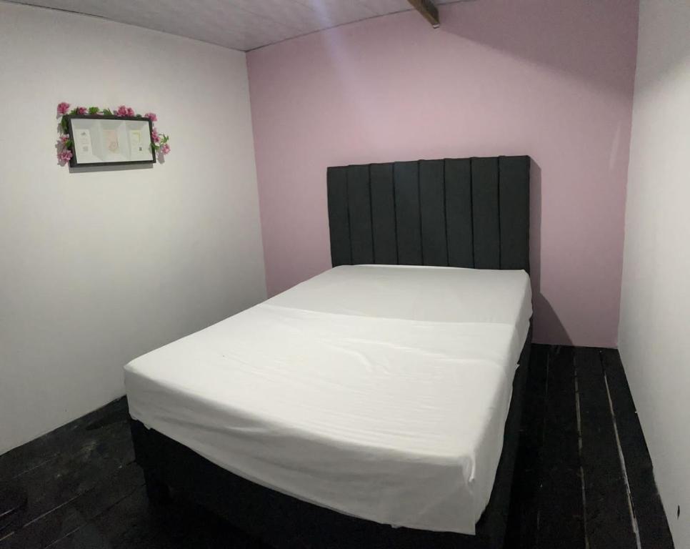 a small bedroom with a white bed with a black headboard at MIRADOR DE BARU in Cartagena de Indias