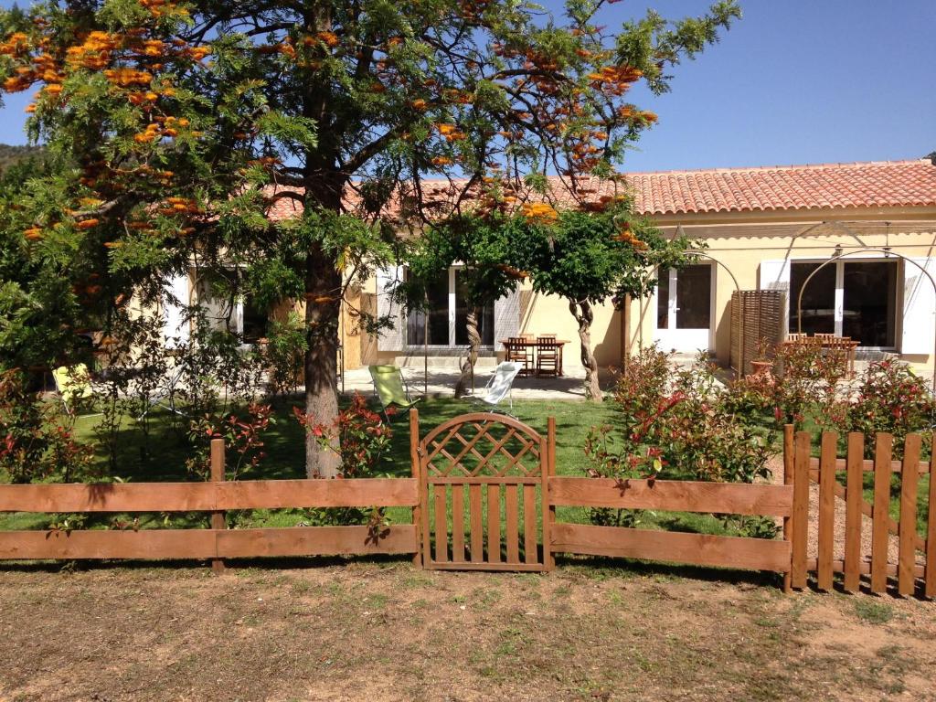 una recinzione di legno di fronte a una casa con un albero di A FATA DI L'ORTOLO gîtes à la ferme a Sartène