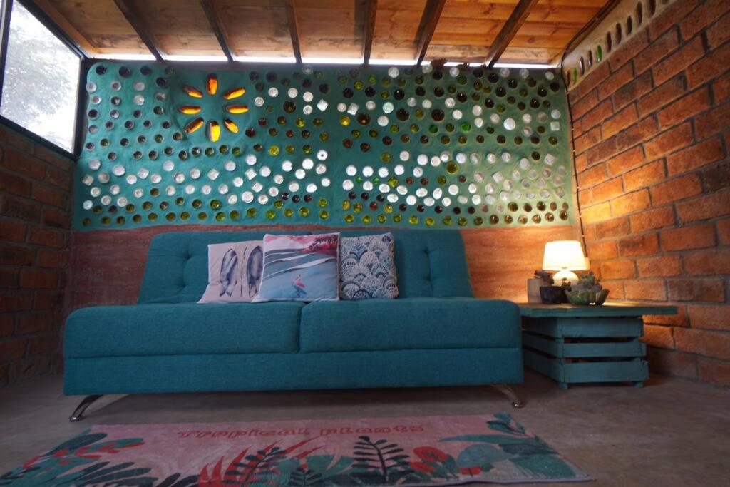 Sofá azul en una habitación con pared de ladrillo en Charming - 2 Storey Eco-Home, en Olón