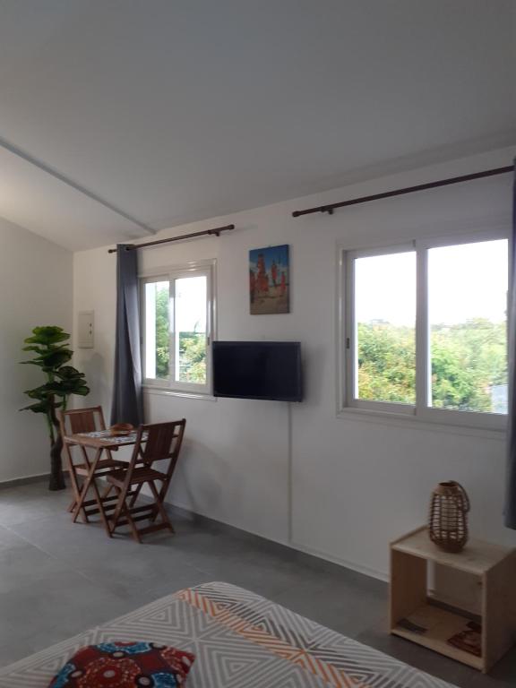 a bedroom with a bed and a table and windows at Studio Cosy AFWA in Les Abymes