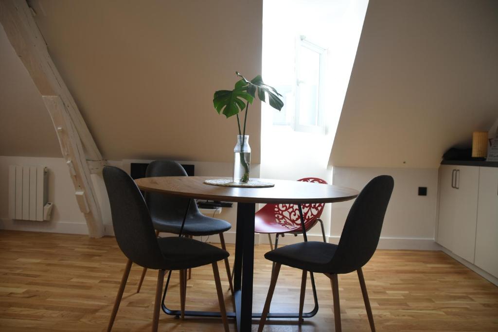 una mesa con sillas y un jarrón con una planta. en Quiétude au Bord de Loire. en Orléans