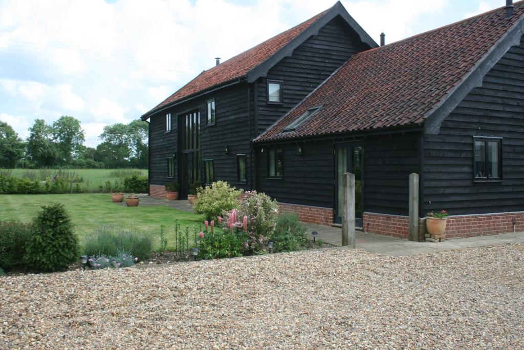 a black house with a garden in front of it at Red House Farm Bed & Breakfast in Tivetshall Saint Margaret