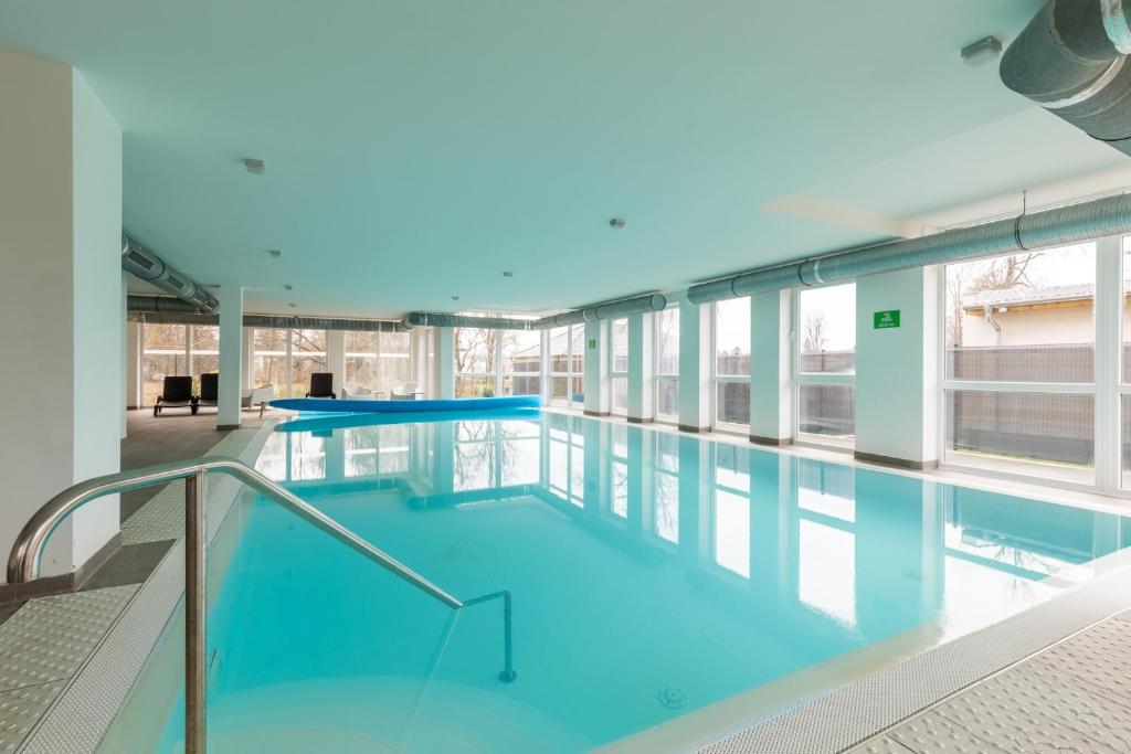 - une grande piscine d'eau bleue dans un bâtiment dans l'établissement Fresh Green Wellness Apartman By BLTN Siófok, à Siófok