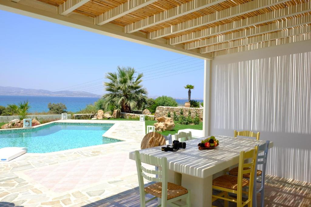a dining room with a table and a swimming pool at Valea Villa in Agios Prokopios