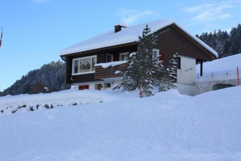 een huis met sneeuw op de grond ervoor bij Casa Uccello in Wildhaus